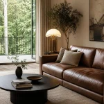 Salon contemporain avec canapé noir, lampe art déco moderne, table basse noire et balcon avec vue sur la forêt